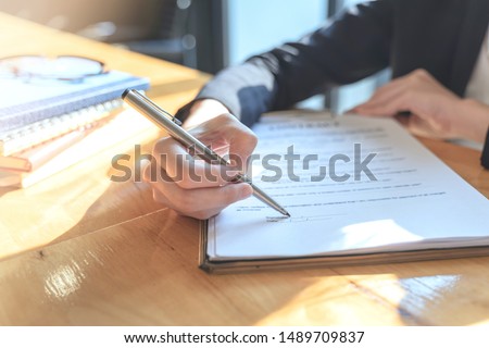 Businesswoman point to a contract paper with their pen and advise customers to sign their names. Points on signature line on contract in office. Royalty-Free Stock Photo #1489709837
