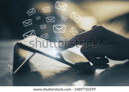 Side view of hand using tablet with glowing email network on blurry background. E-mail marketing, message and communication concept. Multiexposure 