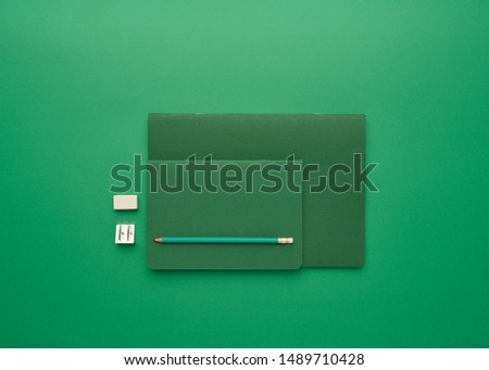 notebook on a green background, back to school, student accessories, free space for an inscription, lay flat