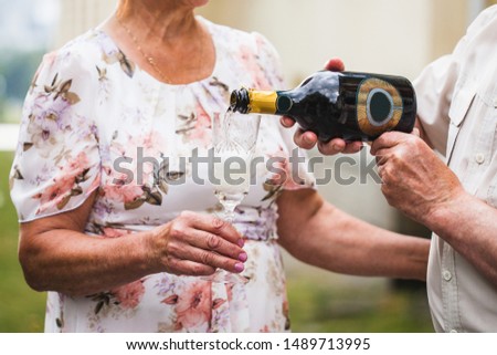 A man pours champagne or white wine into a glass of his beloved woman, alcoholic beverages, anniversary celebration, birthday