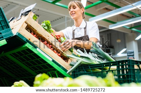 Woman working in a supermarket sorting fresh fruit and vegetables