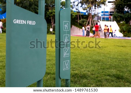 Green metal sign board with space and prohibition sign to do not littering , smoking and drink next to green field, The atmosphere of people meeting in the park.