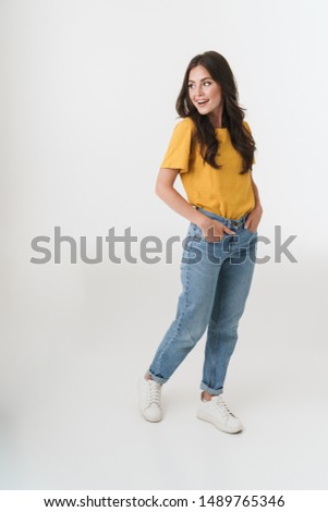 Full length image of attractive brunette woman wearing casual clothes smiling and looking at copyspace isolated over white background