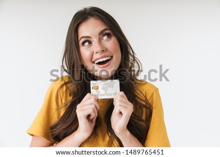 Image of caucasian brunette woman wearing casual clothes smiling and holding credit card isolated over white background