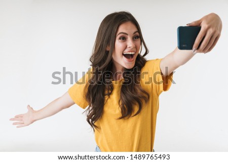Image of excited brunette woman laughing while taking selfie photo on cellphone isolated over white background
