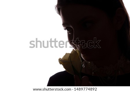 Young woman sniffs a flower - horizontal isolated silhouette of a side view