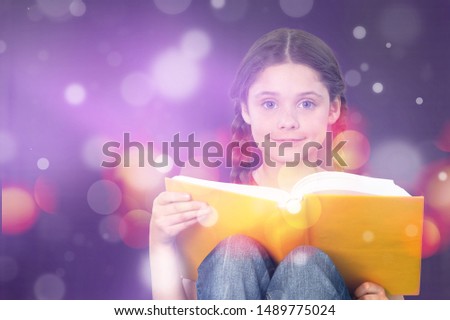 Cute little boy reading magic book on dark color background