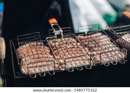 Sausages on grill at bbq party.Close-up of delicious chicken or pork sausages on BBQ. Unrecognizable cook preparing tasty sausages on grill.