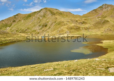 mountaineers and tents on the high mountain lake called Ibón de Escalar in the Pyrenees