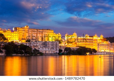 View of famous romantic luxury Rajasthan indian tourist landmark - Udaipur City Palace in the evening twilight with dramatic sky - panoramic view. Udaipur, India Royalty-Free Stock Photo #1489782470