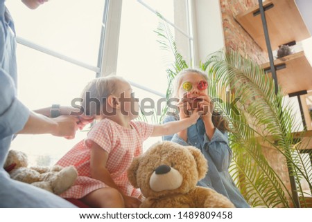 New life. Young mother and her daughters moved to a new house or apartment. Look happy and confident. Moving, relations, lifestyle concept. Playing together, eating sweets and laughting.