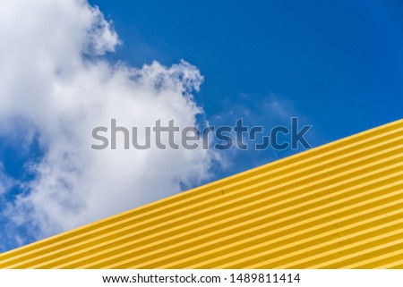Yellow roof against cloudy blue sky as background.