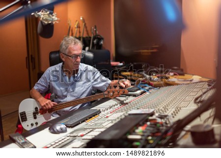 Male middle aged recording engineer in a recording studio sitting at a multi channel console