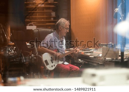 Male middle aged recording engineer in a recording studio sitting at a multi channel console