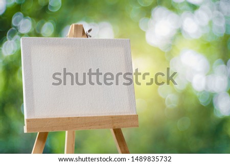 White empty artistic canvas on an easel and green bokeh background