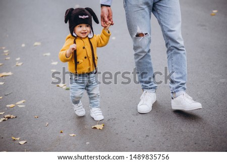 Dad mom and little son are walking in the autumn forest. Falling yellow leaves.Family running, having fun and playing with the baby.