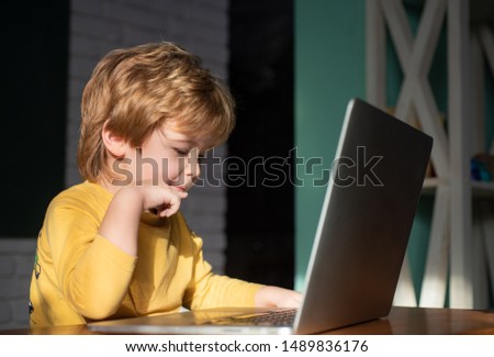 Children with laptop having fun and learning in summer. Happy little child, adorable blonde toddler boy enjoying modern generation technologies. Playing indoors using laptop pc with touchscreen.