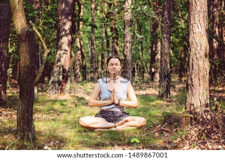 young woman meditating alone and silent in summer forest