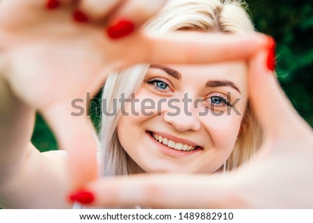 Portrait of beautiful blonde girl smiling making frame with hands and fingers with happy face. Creativity and photography concept