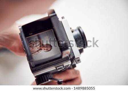 Photographer Looking Into Viewfinder Of Vintage Medium Format Camera On Photo Shoot