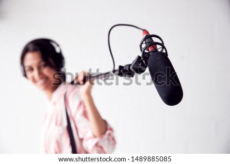 Portrait Of Female Sound Recordist Holding Microphone On Video Film Production In White Studio