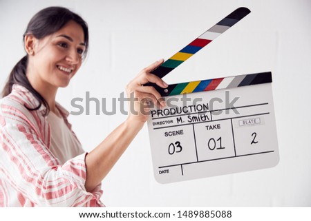 Female Videographer Holding Clapper Board On Video Film Production In White Studio
