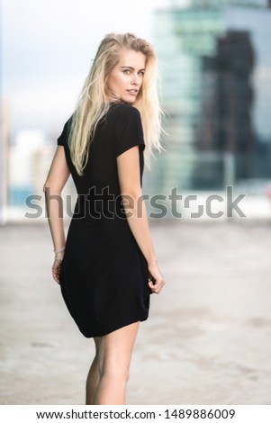 Portrait of young beautiful woman in black dress turning around and looking at the camera while walking. Fashion shooting. Vertical shot. Selective focus