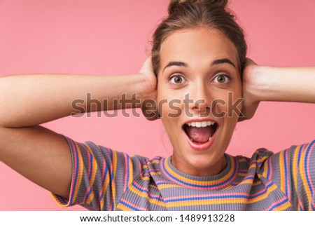 Image closeup of joyful beautiful woman screaming and covering her ears with hands isolated over pink background