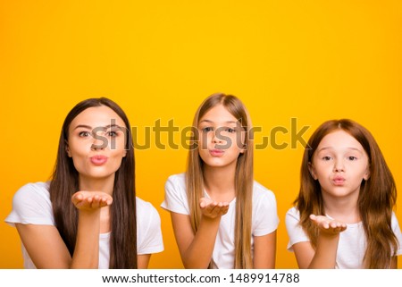Photo of three coquette sister ladies sending air kisses wear casual white t-shirts isolated yellow background