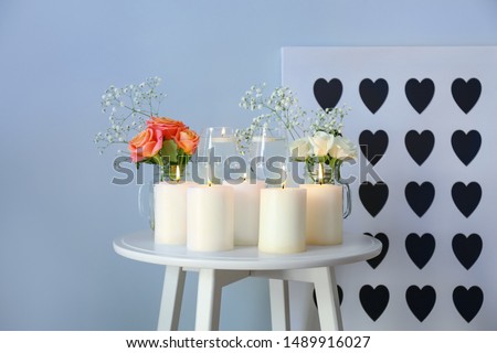 Beautiful burning candles with rose flowers on table