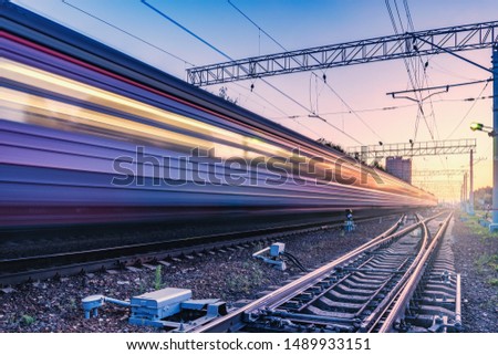 Passenger train moves fast at sunset time. Royalty-Free Stock Photo #1489933151