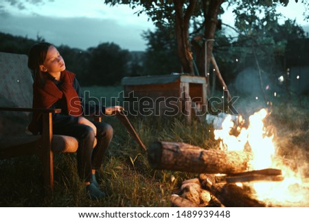Little girl sits by the fire evening nature vacation