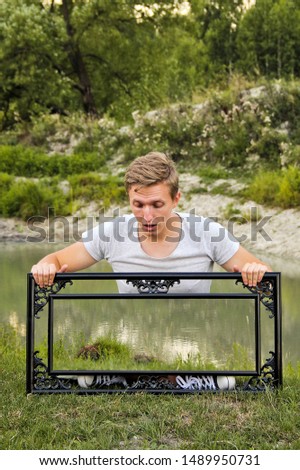 A guy with a picture frame in nature