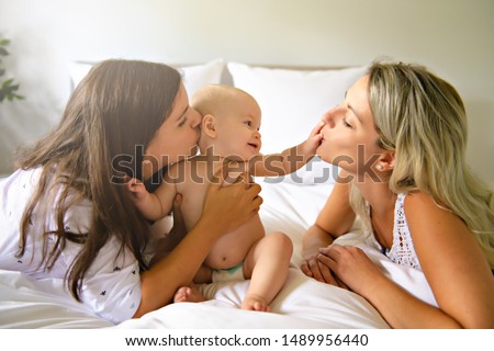Two lesbian mother and baby on bed having fun Royalty-Free Stock Photo #1489956440