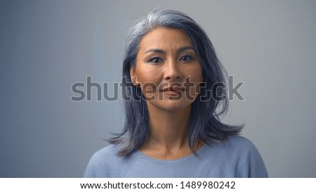 Good-looking Asian Woman In A Light Sweater Is Posing In Front Of The Camera.She Is Serious And Concentrated.Close-up Shot Royalty-Free Stock Photo #1489980242