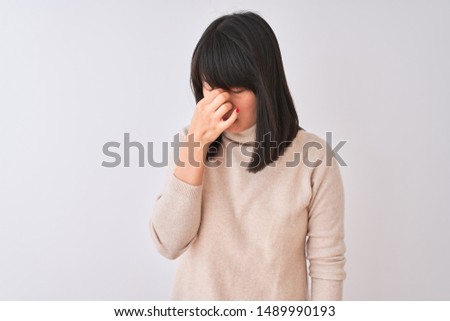 Young beautiful chinese woman wearing turtleneck sweater over isolated white background tired rubbing nose and eyes feeling fatigue and headache. Stress and frustration concept.