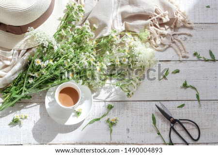 Summer morning table with a cup of coffee and wild flowers under a harsh light