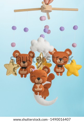 Colorful and eco-friendly children's mobile from felt for children. It consists of bears, stars,moon, clouds and balloons toys. Handmade on blue background.