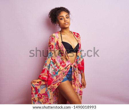 Young beautiful african american woman on vacation standing wearing bikini and colorful caftan