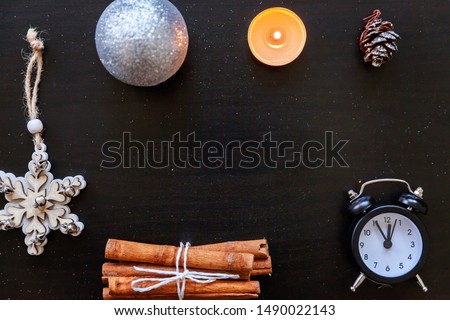 Christmas New Year Composition frame made of winter objects ornament candle clock on dark black background. Flat lay top view copy space. Christmas december time for celebration concept