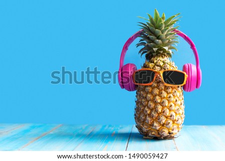 Summer in the party.  Hipster Pineapple Fashion in sunglass and music bright beautiful color in holiday, Creative art fruit for tropical style on the beach vibes, blue background.  Fashion Summer