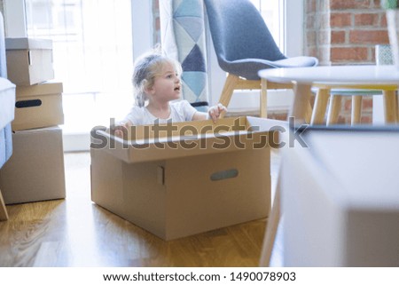 Beautiful toddler child girl playing with boxes at new home
