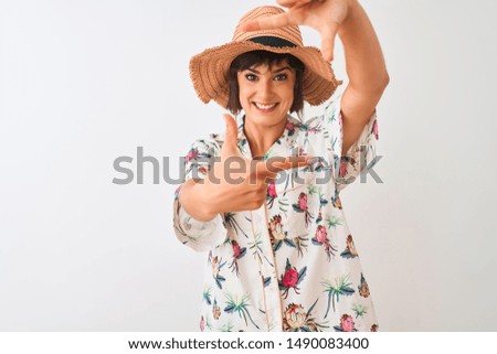 Beautiful woman on vacation wearing summer shirt and hat over isolated white background smiling making frame with hands and fingers with happy face. Creativity and photography concept.