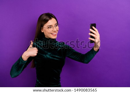 Beautiful lady with telephone hands making selfies raising thumb up wear green velvet turtleneck isolated violet background