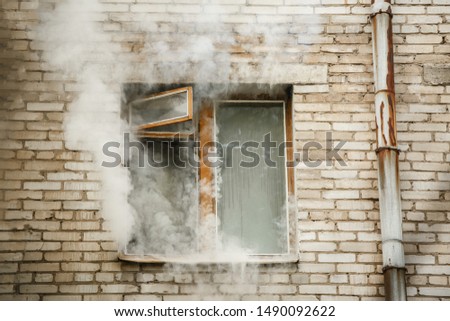 Picture of brick house with smoke coming out of window.