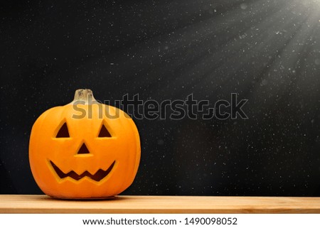 Halloween holiday concept.Jack o lantern pumpkin on black background decor on wooden table with starry night light.Copy space.