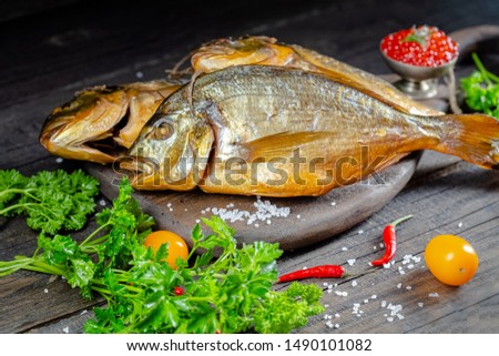 different sea smoked river fish lies on a screw-up rustk on a chopping board and a table, the ropes, slices of lemon and lime are cut whole round, around, with greens light, top side view, around
