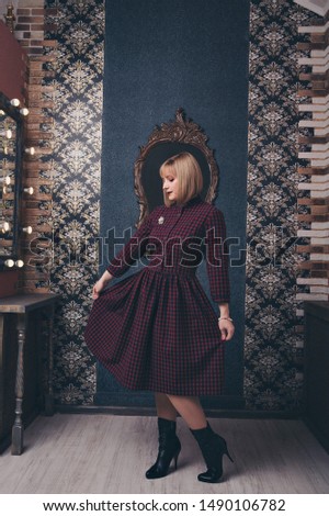 fashionable stylish portrait of a woman with white short hair. model in a purple dress with a brooch near the mirror. work concept, model business