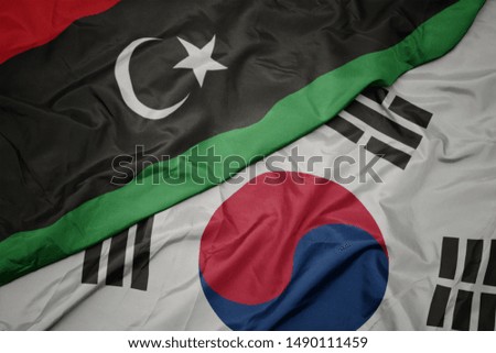 waving colorful flag of south korea and national flag of libya. macro