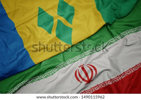 waving colorful flag of iran and national flag of saint vincent and the grenadines. macro